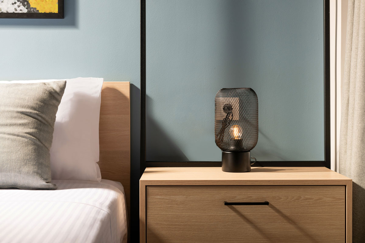 modern black metal edison bulb lamp on wooden bedroom night table in contemporary style gray room interior
