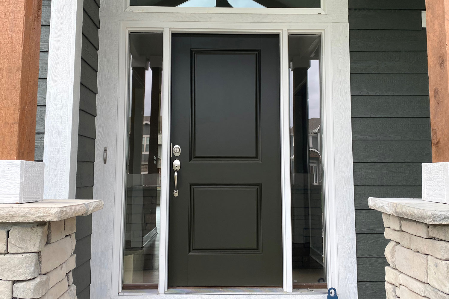 A black front door with white trims and frameless sidelights