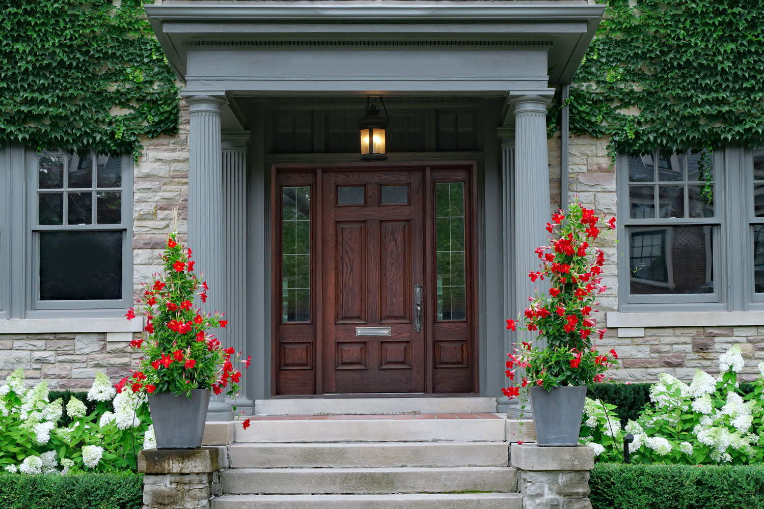 A brown hardwood front door and a gray concrete entryway