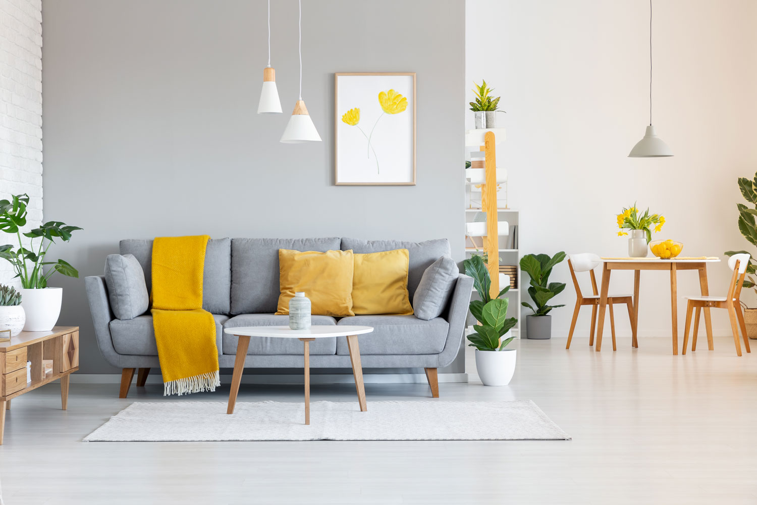 A gray sofa with yellow throw pillows and a white dangling lamps