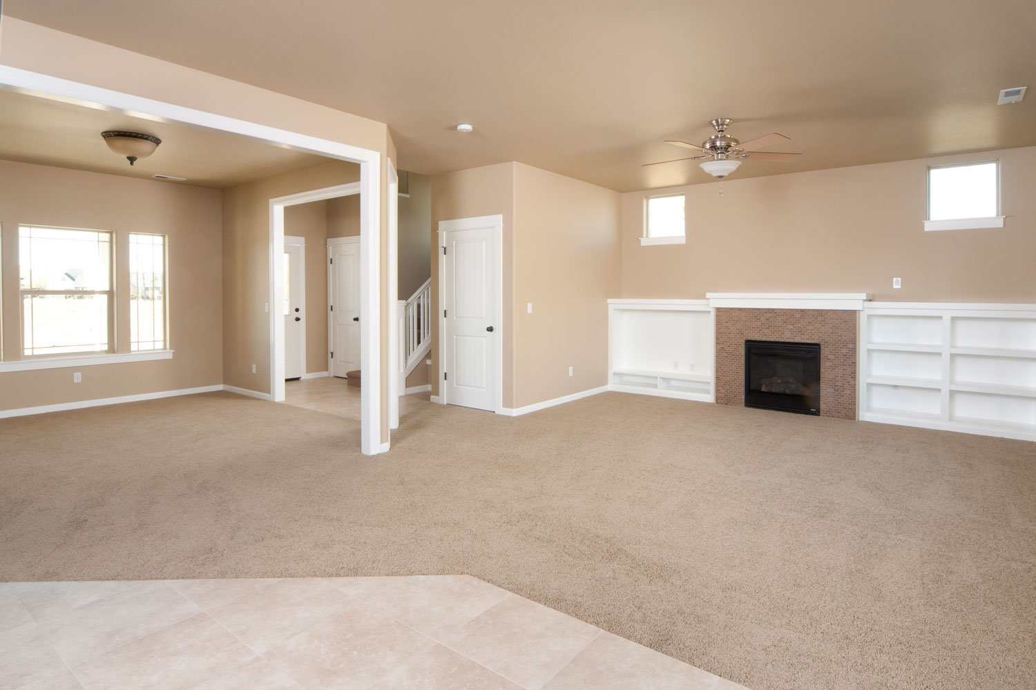 A living room painted in tan, white trims and carpeted flooring