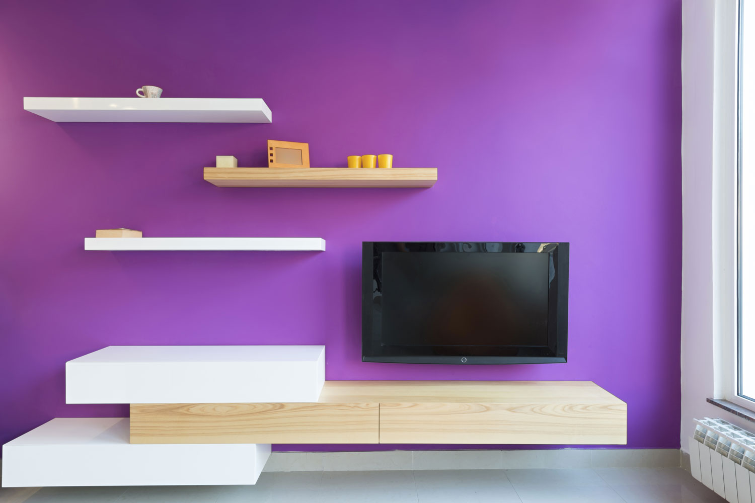 A purple colored accent wall with floating dividers and a small night stand