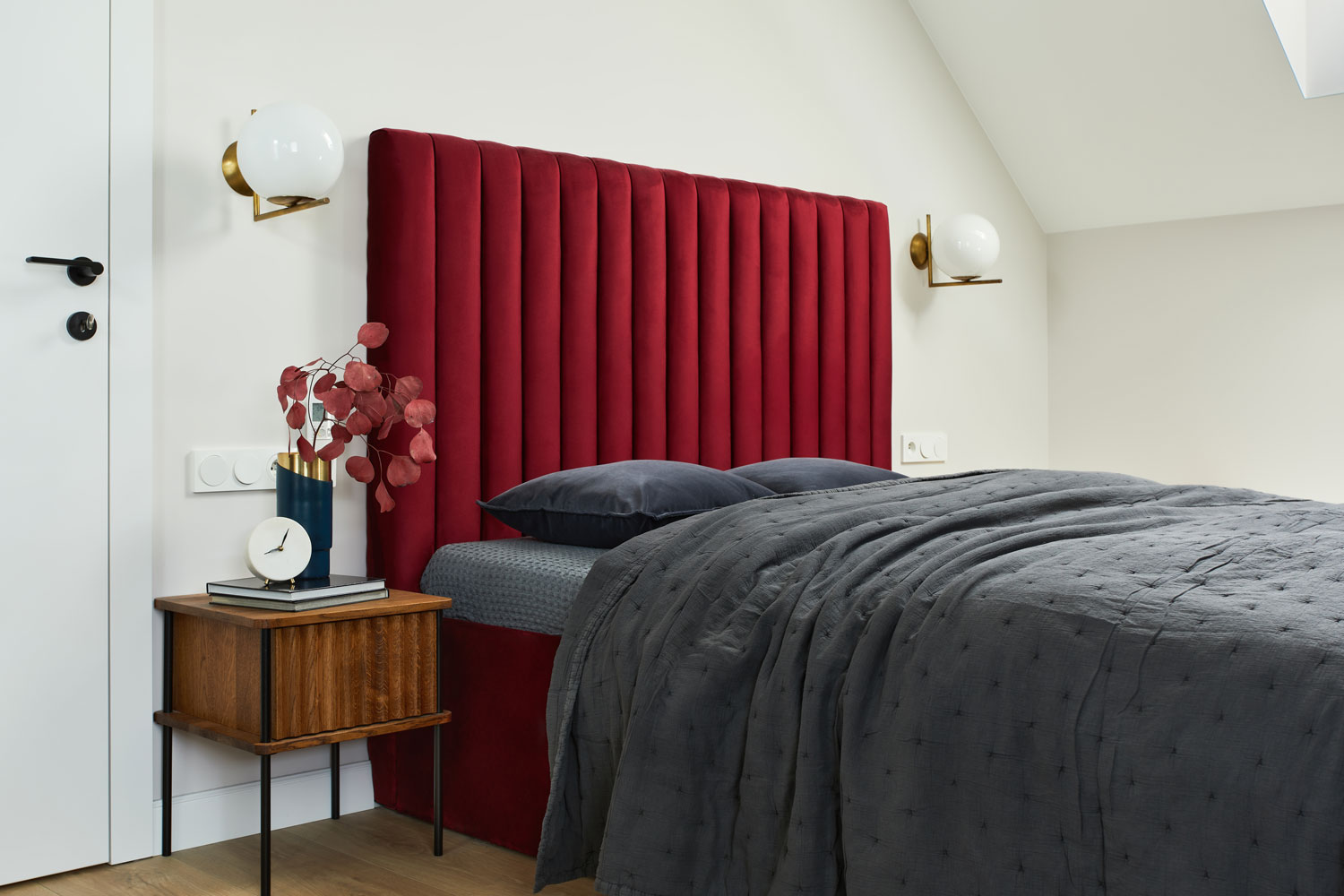 A red headboard for a dark gray bed inside a white bedroom
