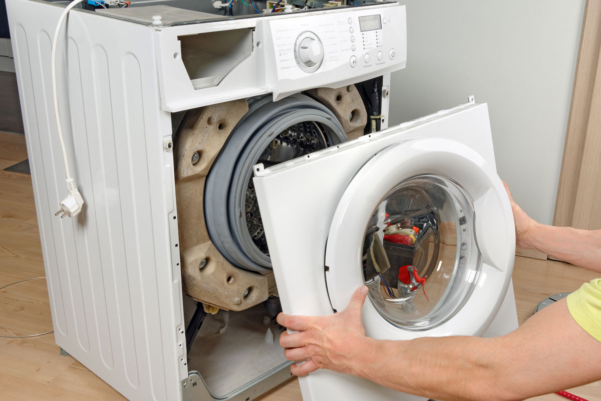 A service technician repairs a damaged washing machine