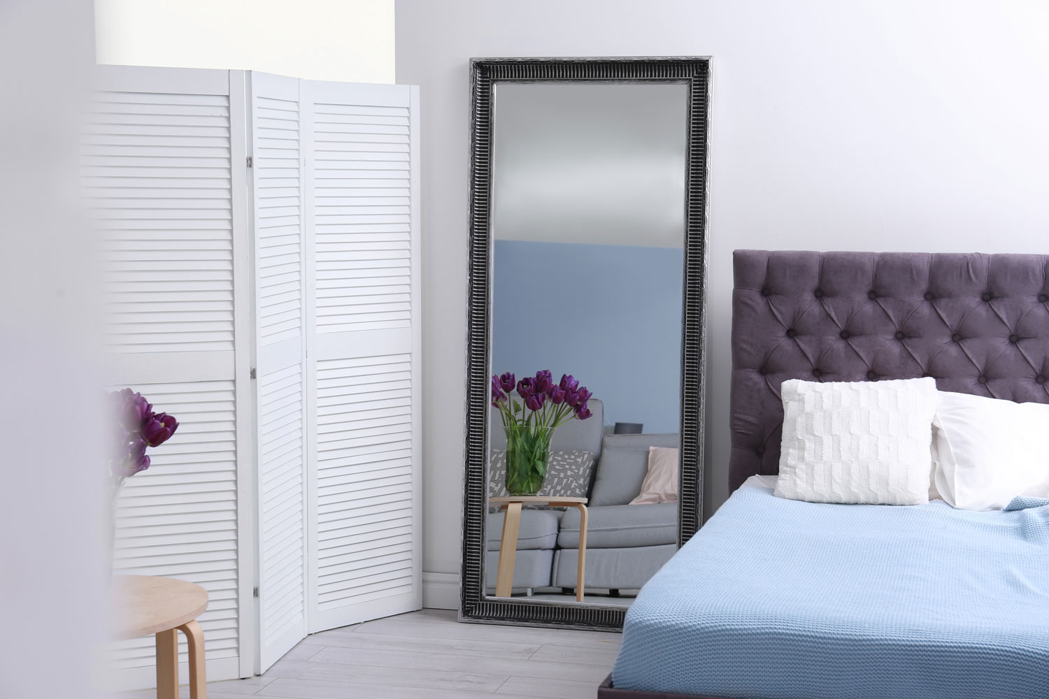 A standing mirror on the corner of the bedroom