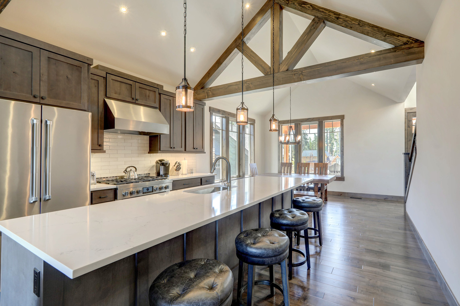 Amazing modern and rustic luxury kitchen with vaulted ceiling and wooden beams, long island with white quarts countertop and dark wood cabinets.
