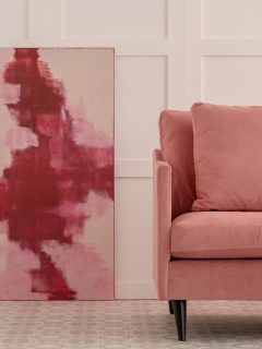 Burgundy and pastel pink abstract painting in white living room interior with velvet sofa