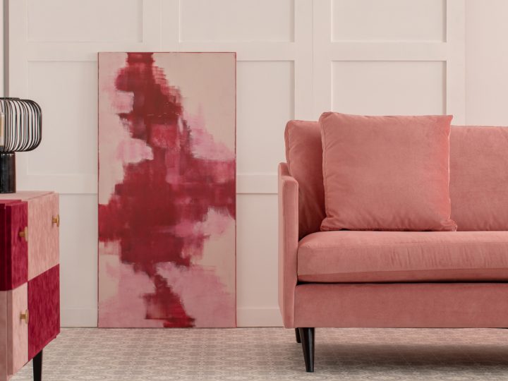 Burgundy and pastel pink abstract painting in white living room interior with velvet sofa