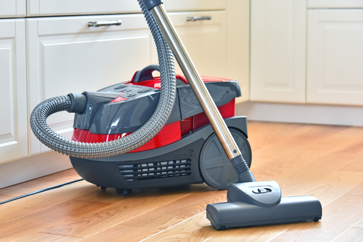 Canister vacuum cleaner for home use on the floor in the apartment.