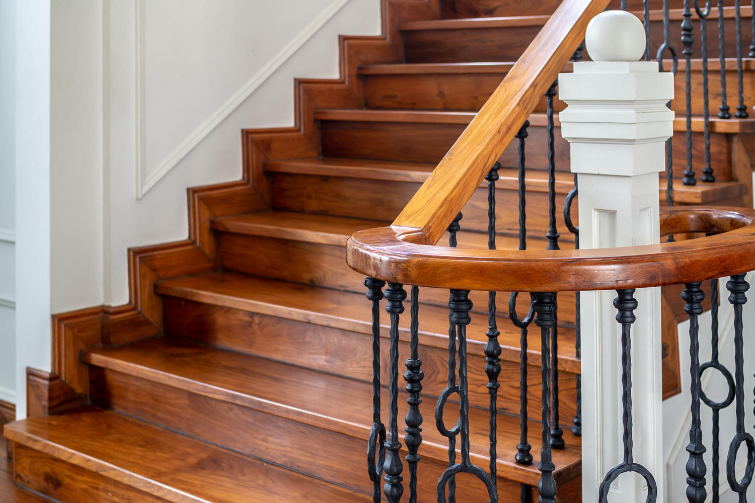Classic vintage elegant wooden staircase with wrought iron railing.