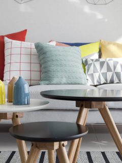 Colorful cushions on a sofa with little vase in foreground, Cushions Too Firm: Here's How To Break In A Couch