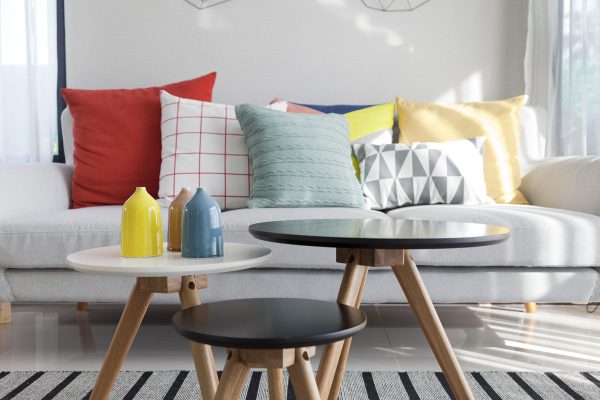 Colorful cushions on a sofa with little vase in foreground, Cushions Too Firm: Here's How To Break In A Couch