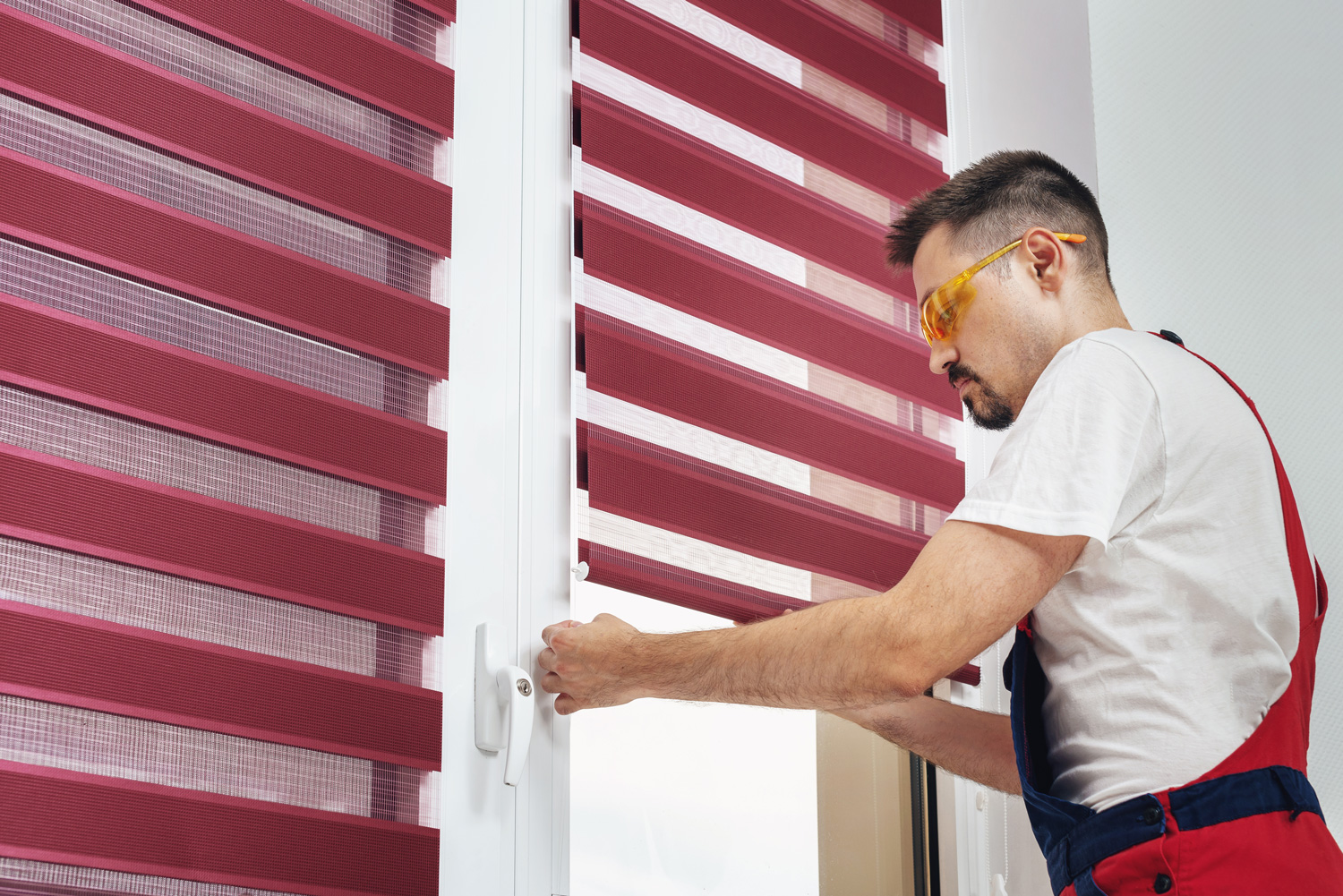 Construction worker man in a uniform installing new window blinds
