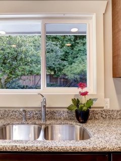 A dark brown kitchen cabinet with sink and granite counter top, Should A Sink Be Centered Under A Window?
