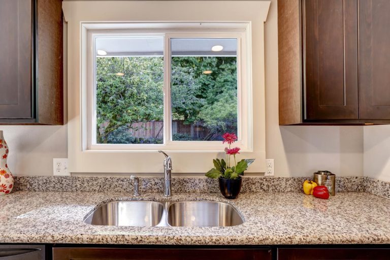 A dark brown kitchen cabinet with sink and granite counter top, Should A Sink Be Centered Under A Window?