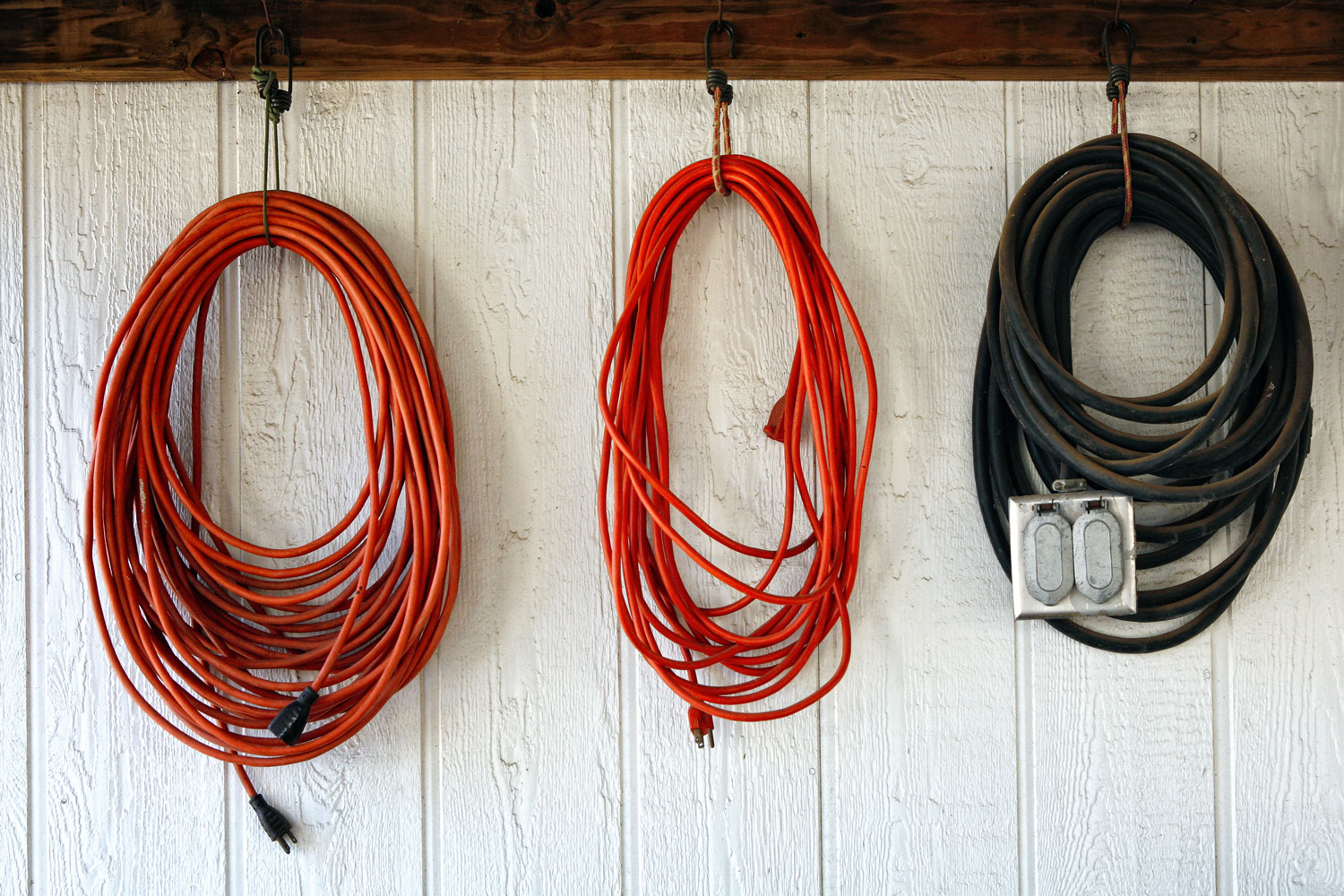 Different lengths and colors of extension cord hanged on the wall