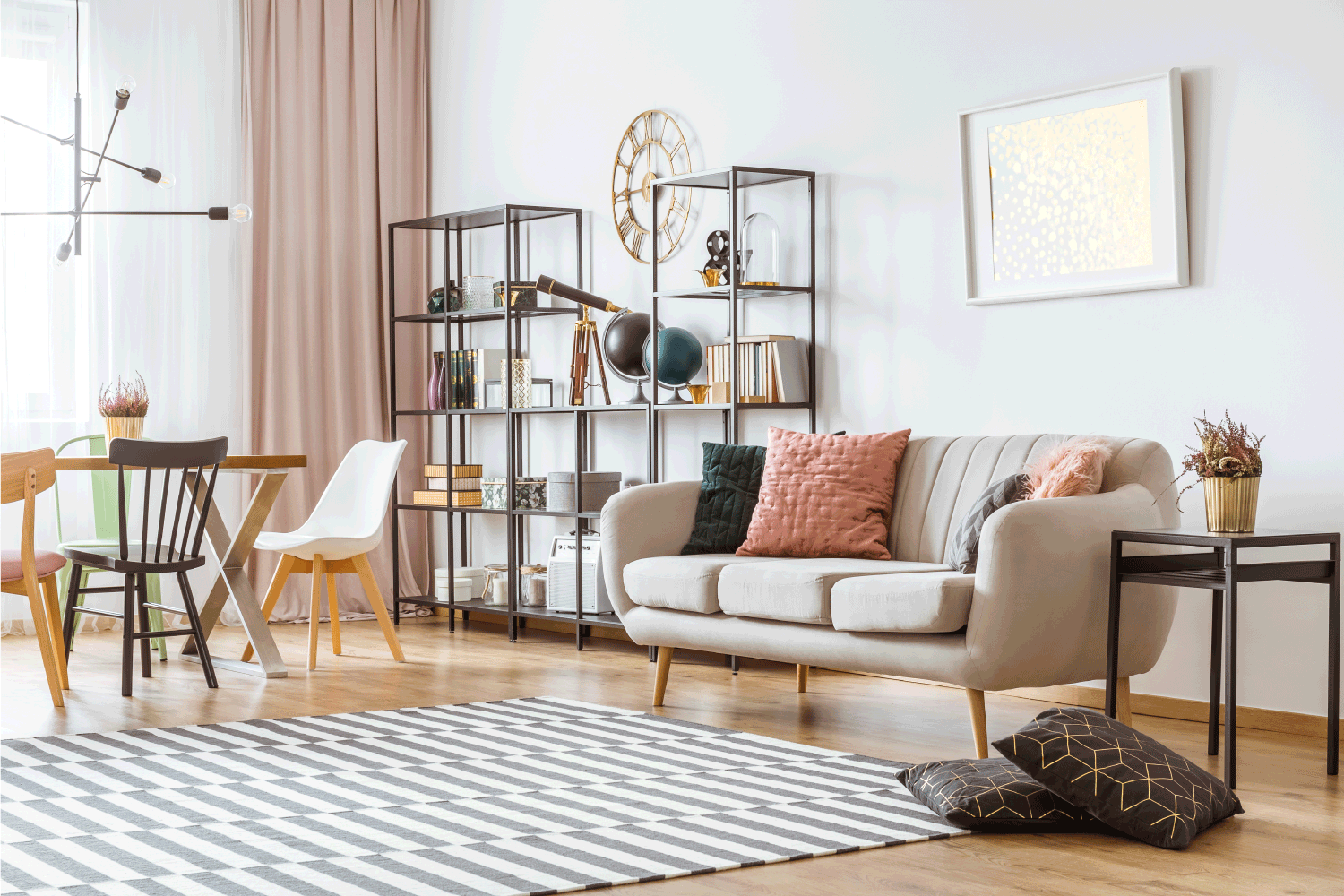 Eclectic Blush Beige Living Room. Painting on white wall above sofa with cushions in living room interior with chairs at the table under metal lamp