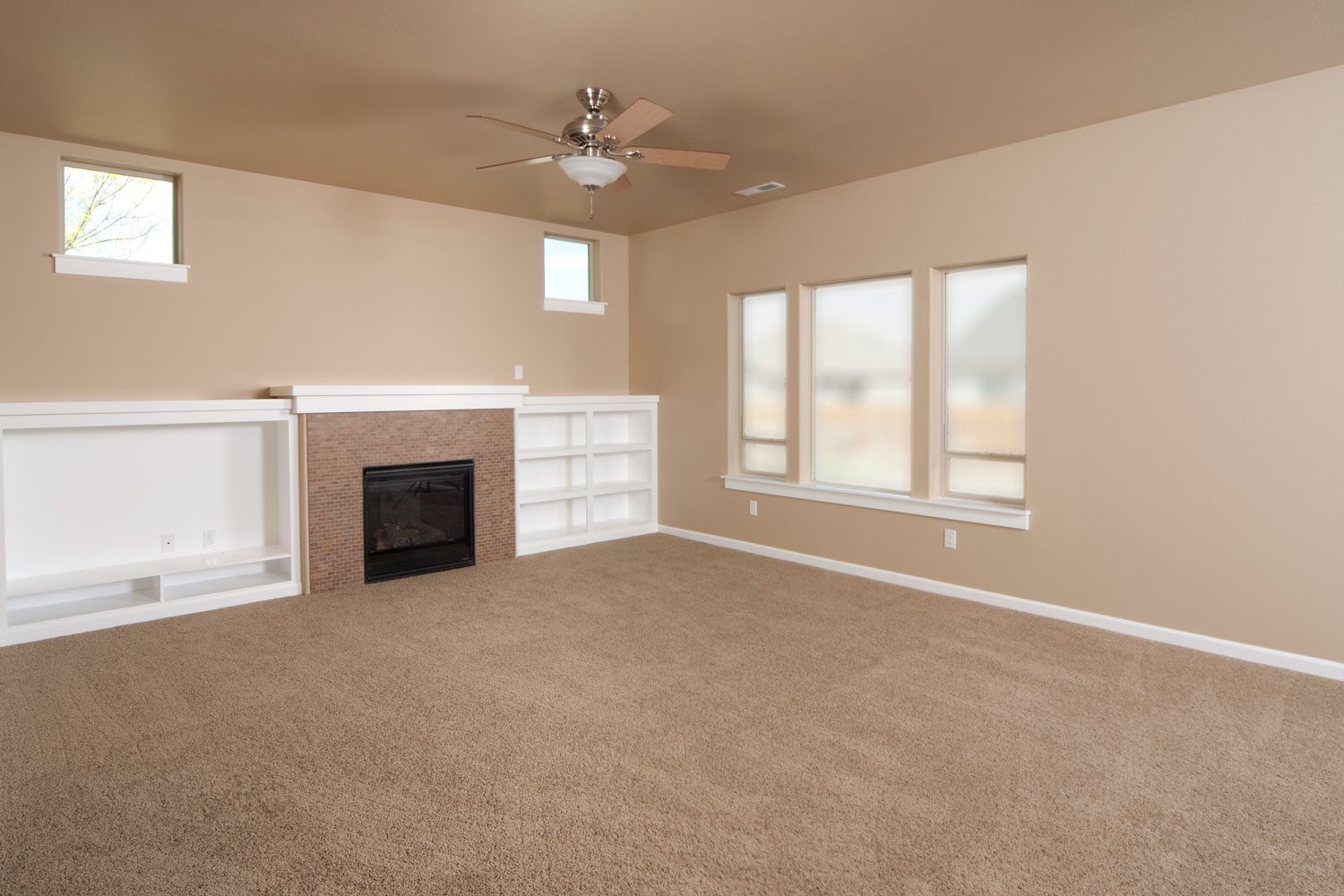 Empty carpeted living room, white trims and tan painted walls