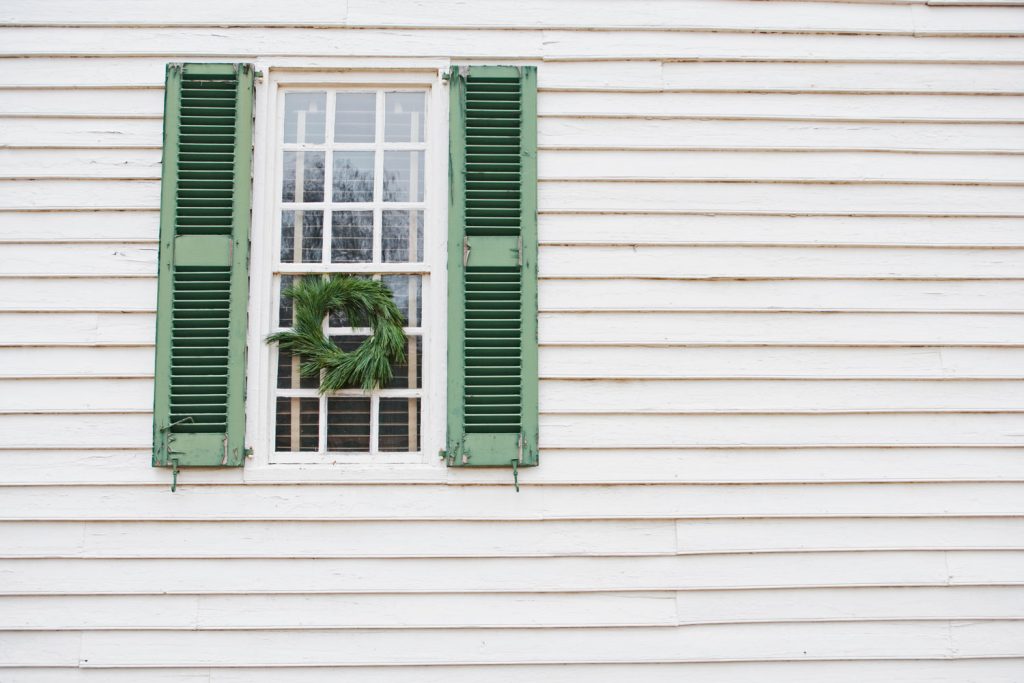Green window shutters and white vinyl siding