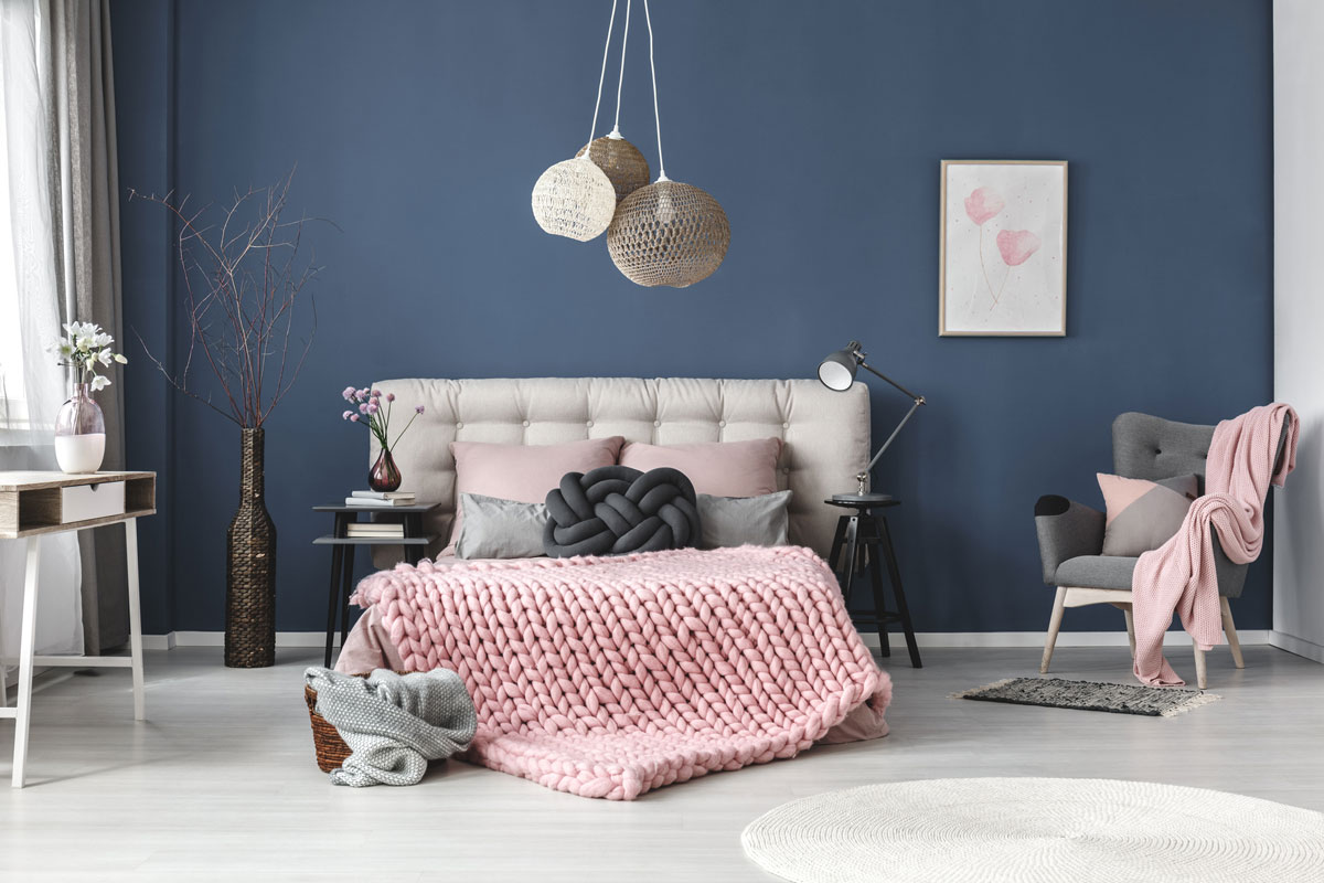 Grey armchair with pink blanket and pastel pillow in bedroom