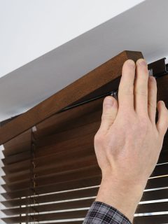 Installing wooden blinds. A man attaches a decorative bar on top, How To Fit And Install Blinds Like A Pro