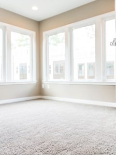 Interior of an empty living room with carpeted flooring, white trims window sills and tan painted walls, Can New Carpet Make You Sick?