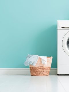 Interior of laundry room with a washing machine on bright teal wall, When To Replace Washer Shock Absorber