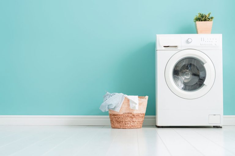 Interior of laundry room with a washing machine on bright teal wall, When To Replace Washer Shock Absorber