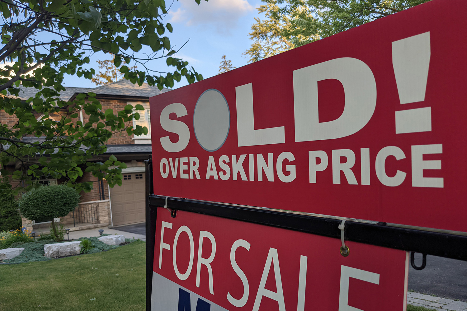 New sign sold over asking price for sale in front of detached house in residential area. Real estate bubble, crash, hot housing market, overpriced property, buyer activity concept.