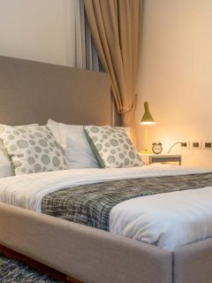 A queen size bed with bed runner and reading lamp in villa, What Size Rug For A Queen Bed?