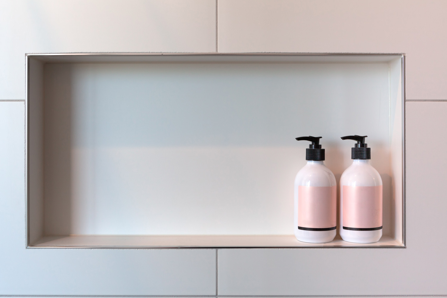 Shampoo and conditioner or shower gel dispensers in a rectangular niche made of white tiles with copy space