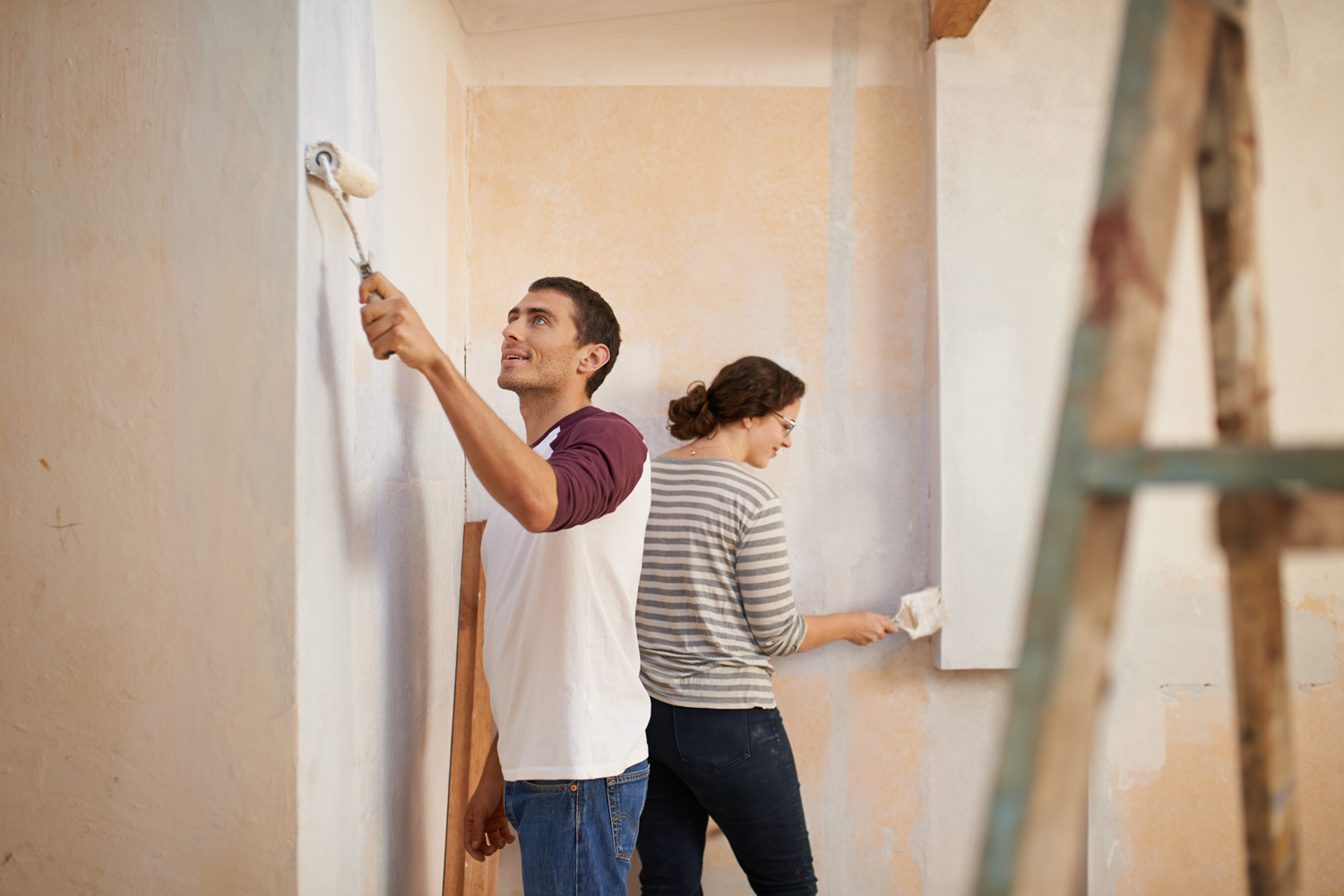 Shot of a young couple painting the walls of their home