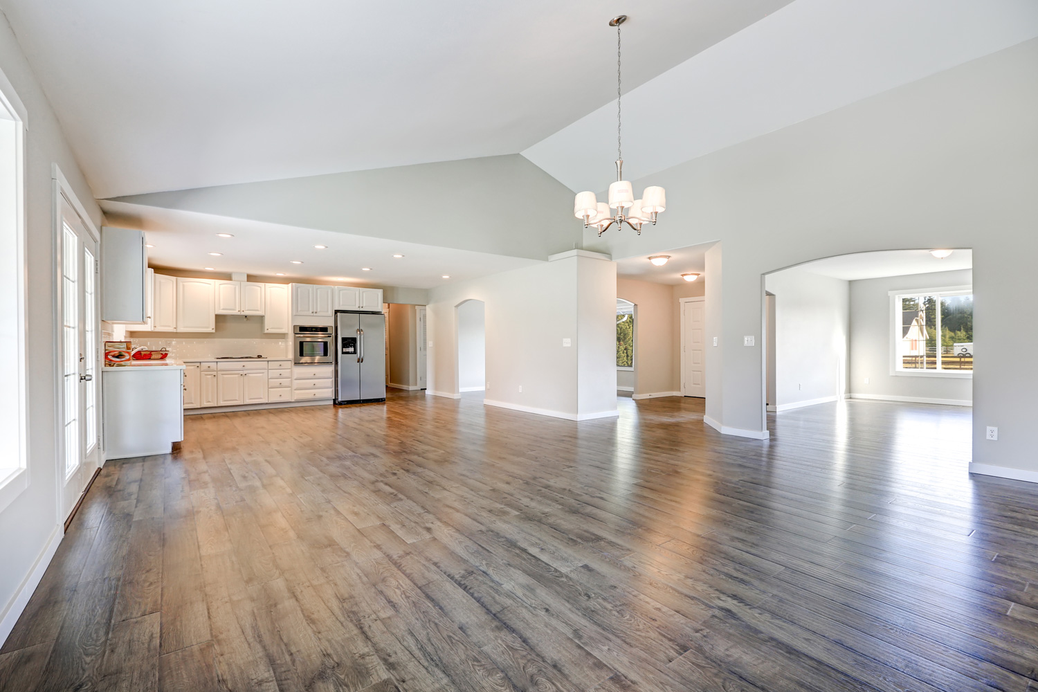 Spacious rambler home interior with vaulted ceiling over glossy laminate floor.