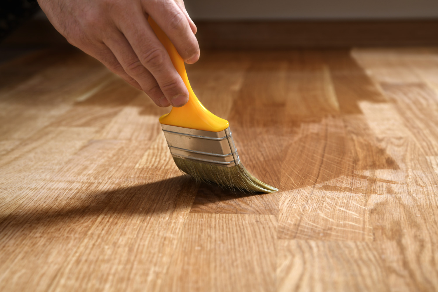 Varnishing lacquering parquet floor by paintbrush 