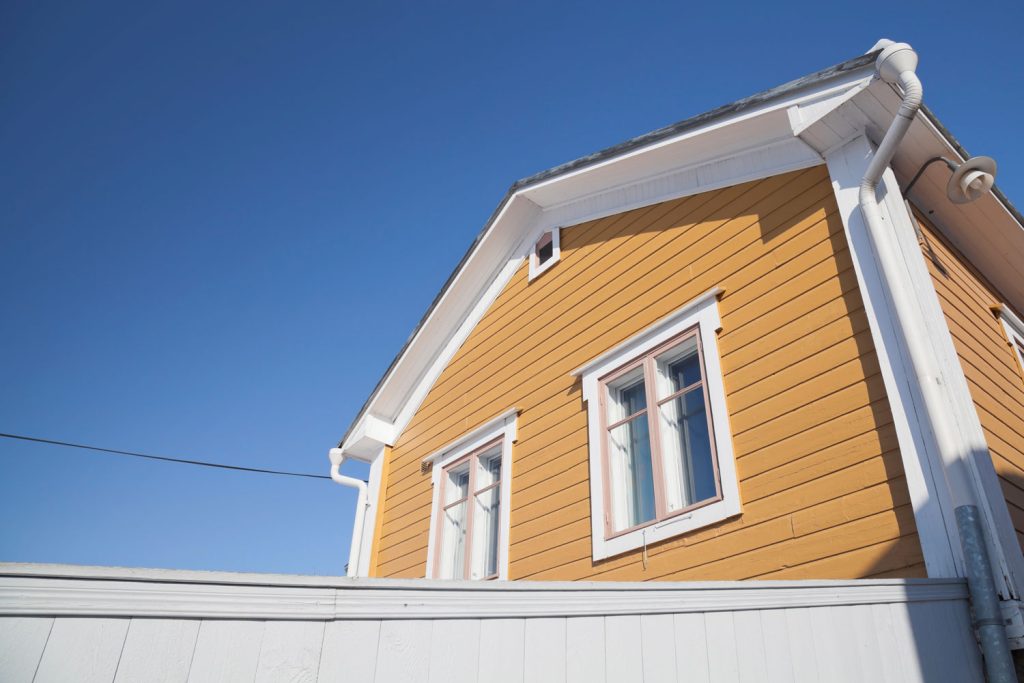 Yellow vinyl siding of a house with white trims