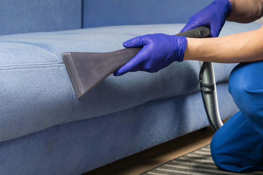 the old blue sofa is cleaned with a vacuum cleaner, with a wet cleaning function to restore the perfect look