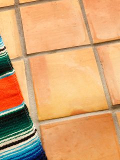 A Mexican blanket sits on a background of saltillo tiles in preparation for a Cinco de Mayo festival celebration, What Flooring Goes With Saltillo Tile?