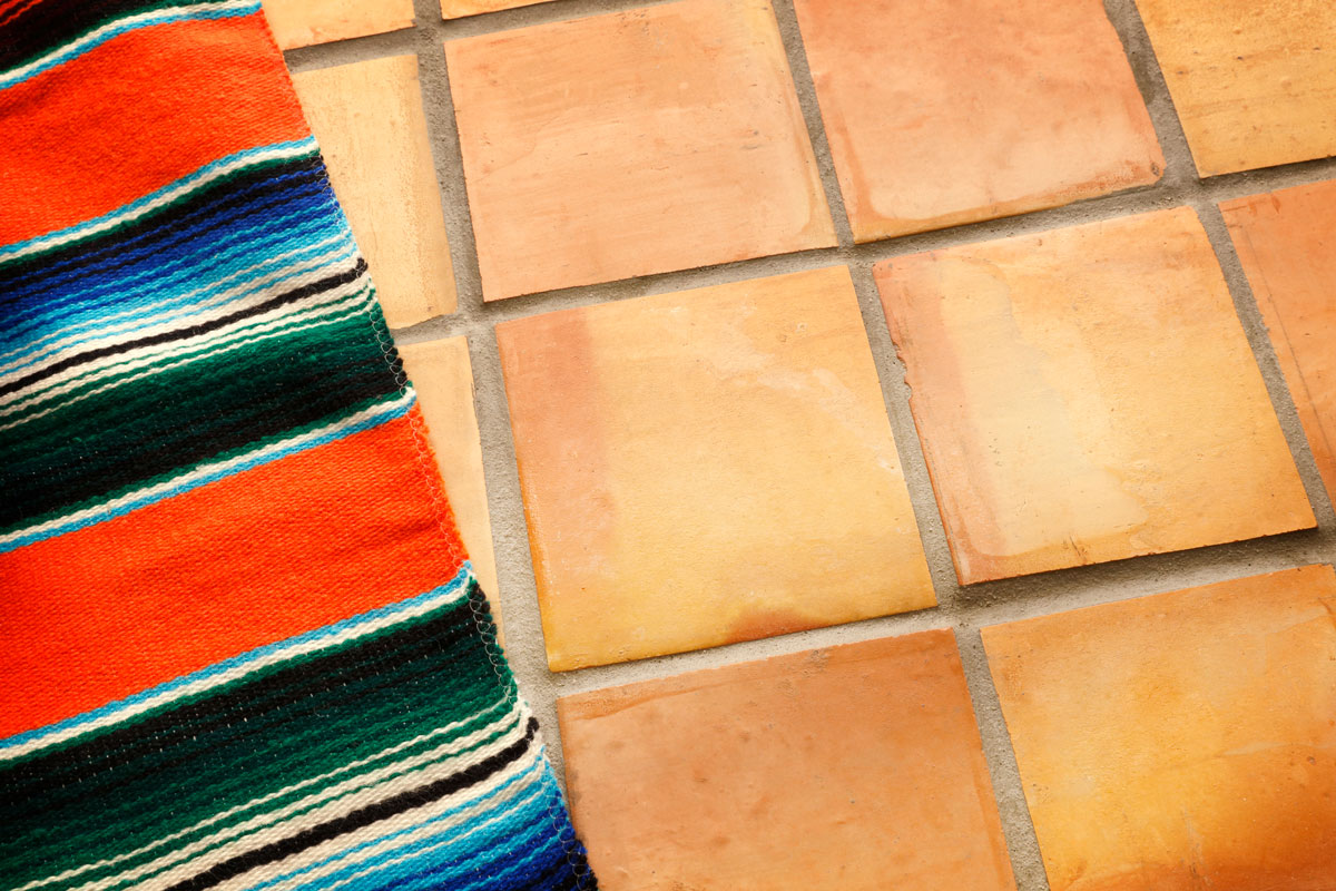A Mexican blanket sits on a background of saltillo tiles in preparation for a Cinco de Mayo festival celebration, What Flooring Goes With Saltillo Tile?
