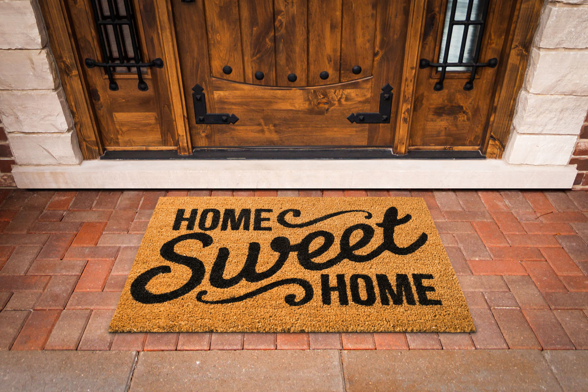 A home sweet home door mat in front of a wooden door