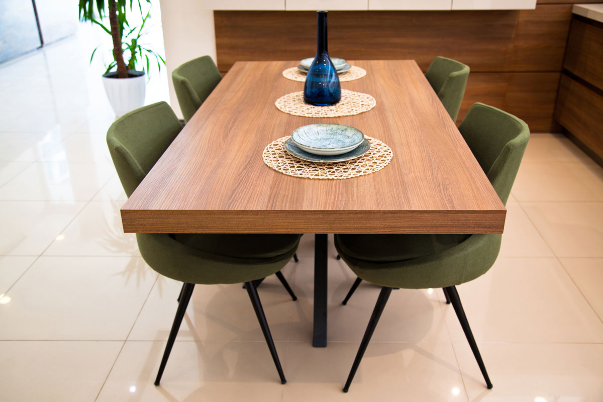 A special walnut dining table with green Nordic chair at a spacious kitchen