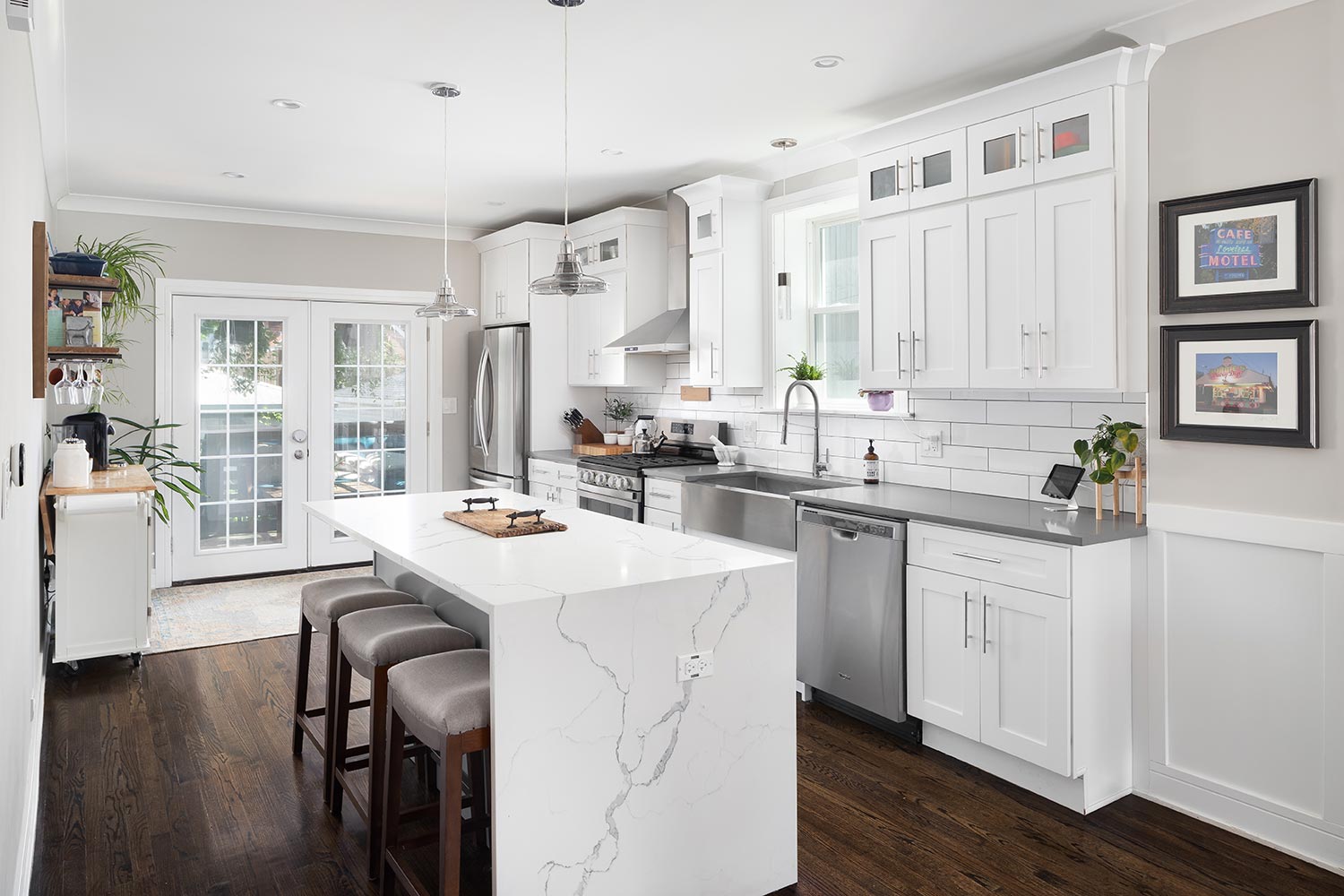 A white renovated kitchen with a waterfall granite island