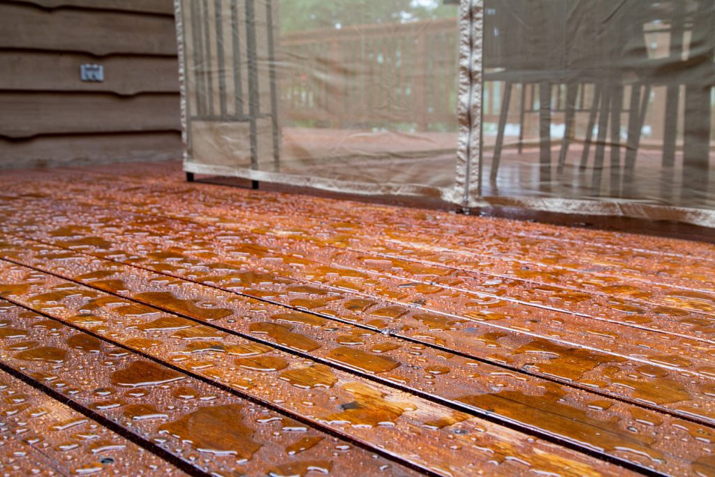 After a spring rain the water puddles on a recently treated wood cottage deck