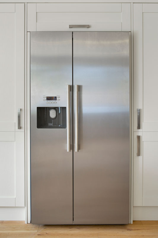 American fridge freezer set into a bank of cream coloured cupboards in a farmhouse-style kitchen
