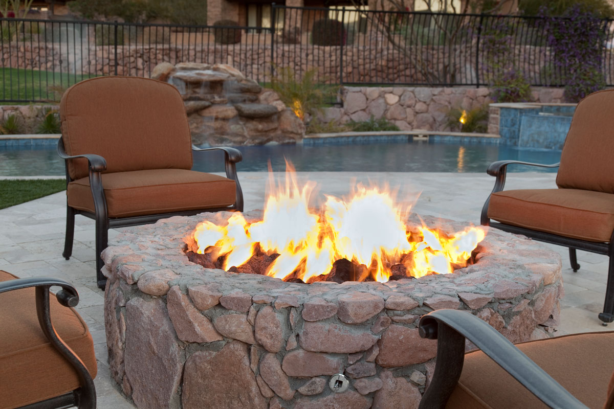 An outdoor fireplace with brown chairs