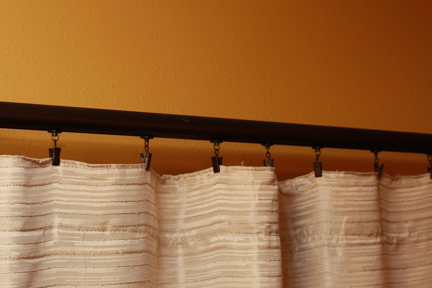 Beige curtains clipped to a curtain rod