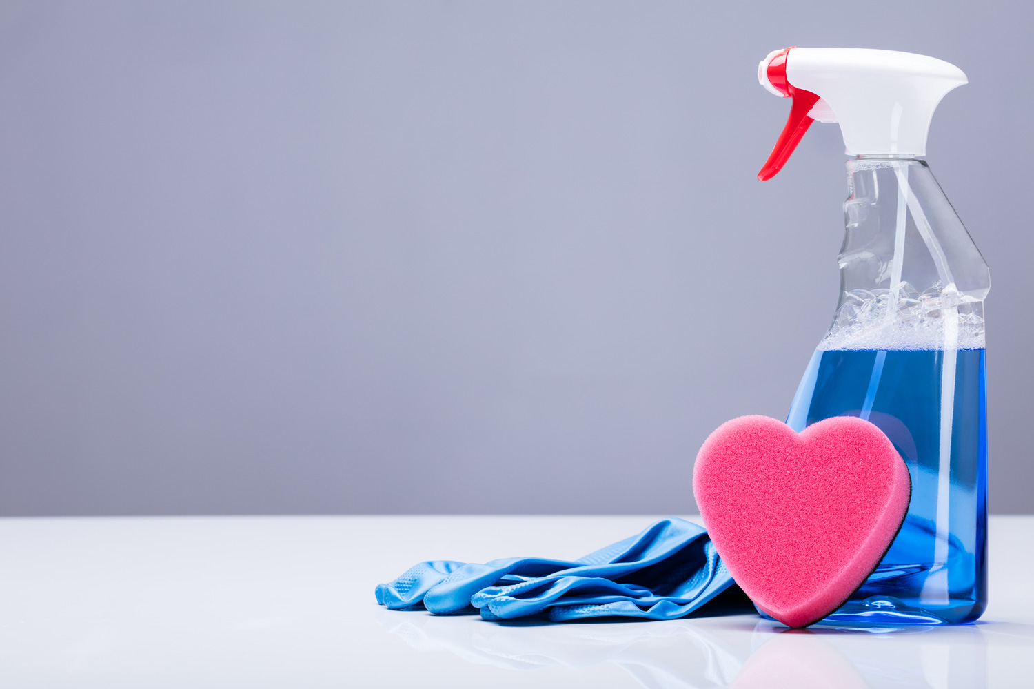 Blue Transparent Cleaning Solution In A Plastic Container With Heart Shape Sponge And Rubber Gloves