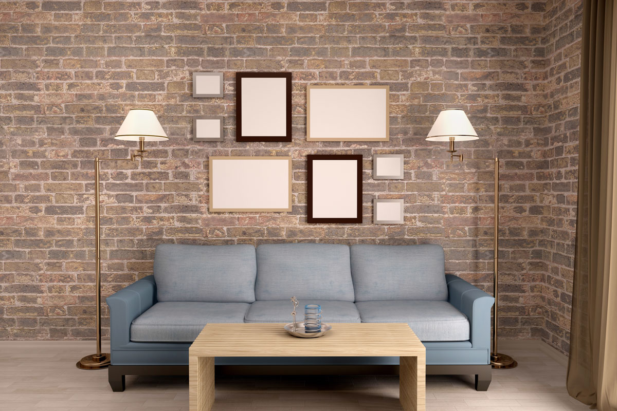 Brick brown wall of interior living room with gray sofa with brown wood table and lampshade each side of sofa and blank frame