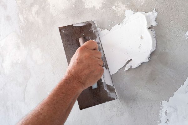 Builder using plastering tool for finishing old wall, Does White Stucco Get Dirty?