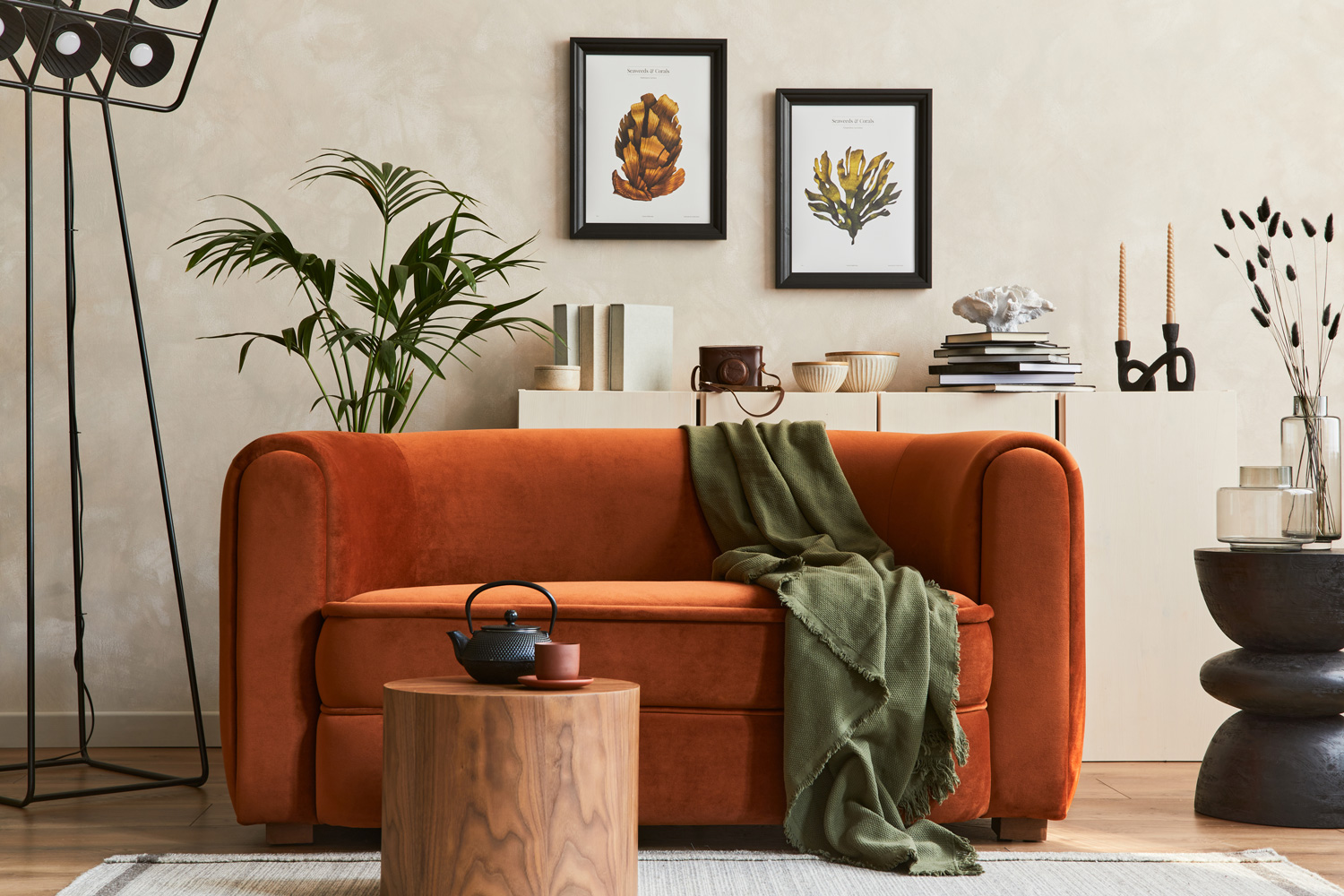 Creative composition of stylish living room interior with mock up poster frame, orange sofa, beige commode, coffee table and stylish personal accessories.