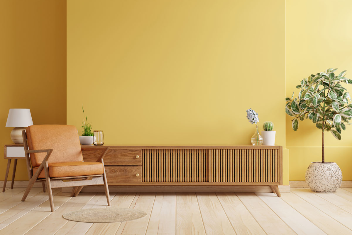Cabinet TV in modern living room with leather armchair and plant on yellow wall